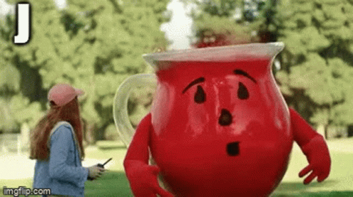 A Woman Is Talking On A Cell Phone Next To A Large Red Pitcher With Arms And Legs . GIF