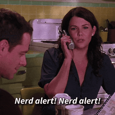 A Woman Is Talking On A Cell Phone While A Man Looks On And Says Nerd Alert ! Nerd Alert ! GIF