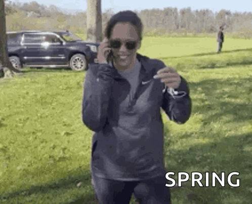 A Woman Is Talking On A Cell Phone While Standing In A Field . GIF