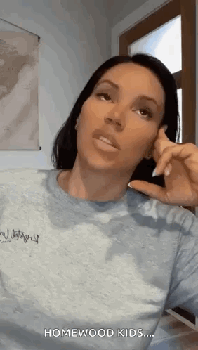 A Woman Is Talking On A Cell Phone While Wearing A Blue Shirt . GIF