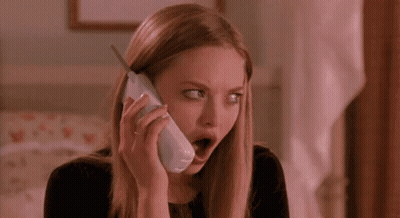 A Woman Is Talking On A Cell Phone With Her Mouth Open And Making A Surprised Face . GIF