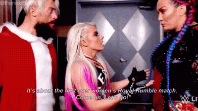 A Woman Is Talking To A Man And Another Woman While Wearing A Santa Claus Outfit . GIF