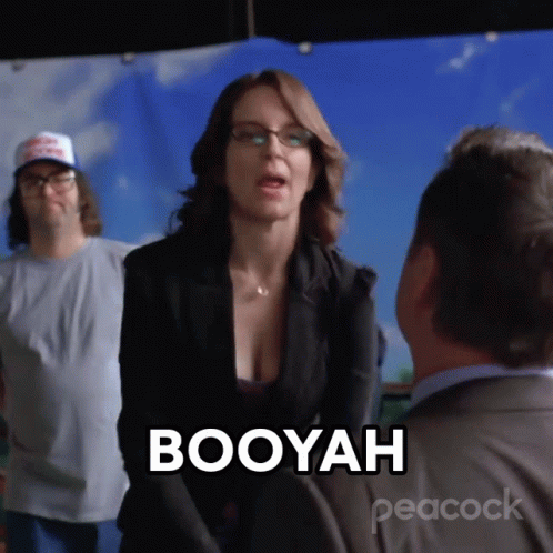 A Woman Is Talking To A Man And The Word Booyah Is On The Screen Behind Her GIF