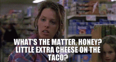 A Woman Is Talking To Another Woman In A Grocery Store While Holding A Taco . GIF