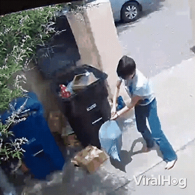 A Woman Is Throwing A Bag Of Trash Into A Garbage Can On The Sidewalk . GIF