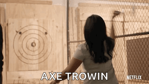 A Woman Is Throwing An Axe At A Target And The Words Axe Trowin Are On The Screen GIF