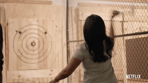 A Woman Is Throwing An Axe At A Target That Says Netflix GIF