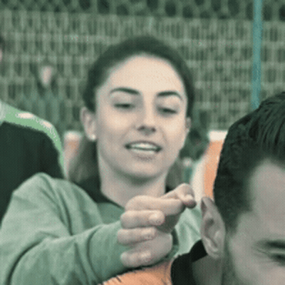 A Woman Is Touching A Man 'S Ear In A Crowd GIF