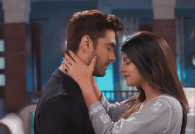 A Woman Is Touching A Man 'S Face While He Looks At Her GIF
