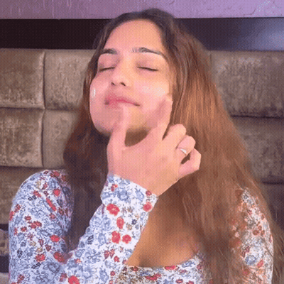 A Woman Is Touching Her Face With Her Hand While Wearing A Ring . GIF