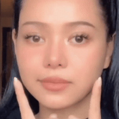 A Woman Is Touching Her Face With Her Hands . GIF