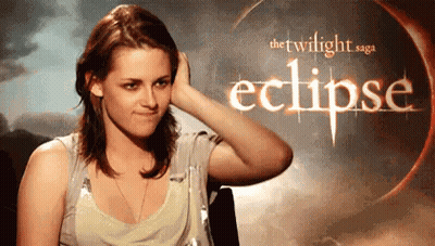 A Woman Is Touching Her Hair In Front Of A Poster For The Twilight Saga Eclipse . GIF