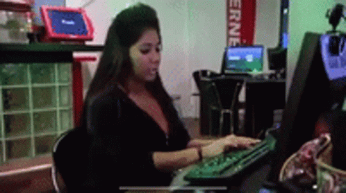 A Woman Is Typing On A Computer Keyboard In Front Of A Sign That Says " Erne " GIF