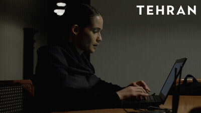 A Woman Is Typing On A Laptop With Tehran In White Letters GIF