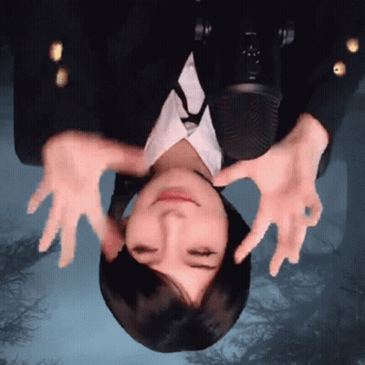 A Woman Is Upside Down In Front Of A Microphone With Her Hands On Her Face GIF