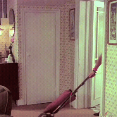 A Woman Is Using A Vacuum Cleaner In A Room GIF
