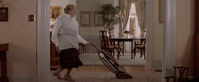 A Woman Is Vacuuming The Floor In A Living Room GIF