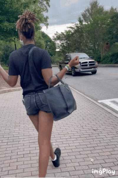 A Woman Is Walking Down A Brick Sidewalk With A Dodge Truck In The Background And The Word Imgplay At The Bottom GIF