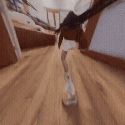 A Woman Is Walking Down A Hallway With A Dog In Her Hand . GIF