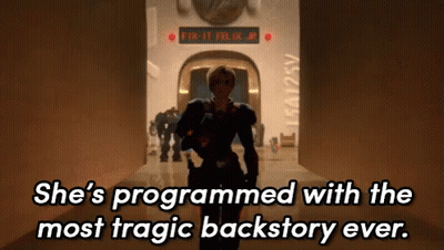 A Woman Is Walking Down A Hallway With The Words She 'S Programmed With The Most Tragic Backstory Ever . GIF