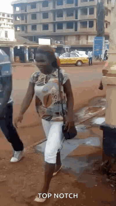 A Woman Is Walking Down A Street With The Words Top Notch Written On The Bottom GIF