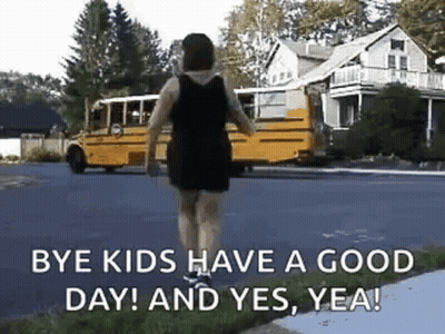 A Woman Is Walking Down The Street In Front Of A School Bus . GIF