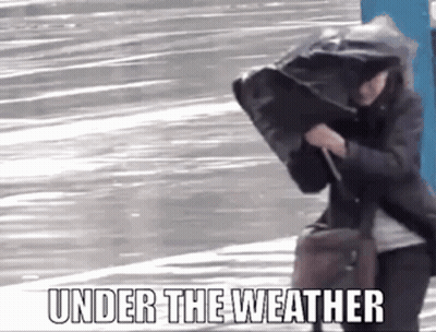 A Woman Is Walking Down The Street With A Bag On Her Head And The Words `` Under The Weather '' Written Above Her . GIF
