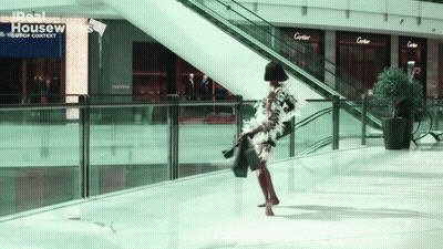 a woman is walking in a mall with a sign that says real housewives on it