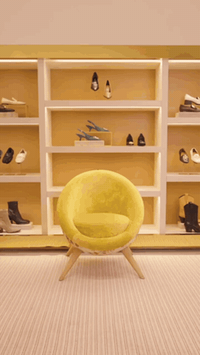 A Woman Is Walking In A Store Holding A Green Purse GIF