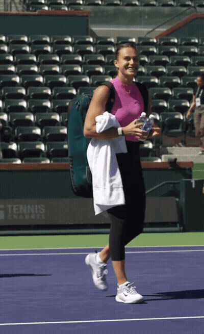 A Woman Is Walking On A Tennis Court With A Tennis Camp Sign In The Background GIF