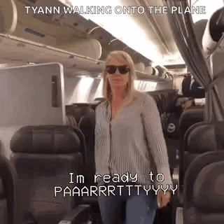 A Woman Is Walking Onto An Airplane Wearing Sunglasses And A Striped Shirt . GIF