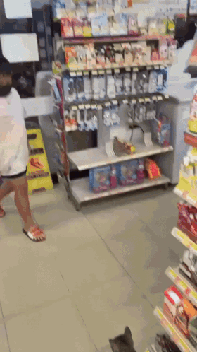 A Woman Is Walking Through A Store Aisle With A Cat GIF