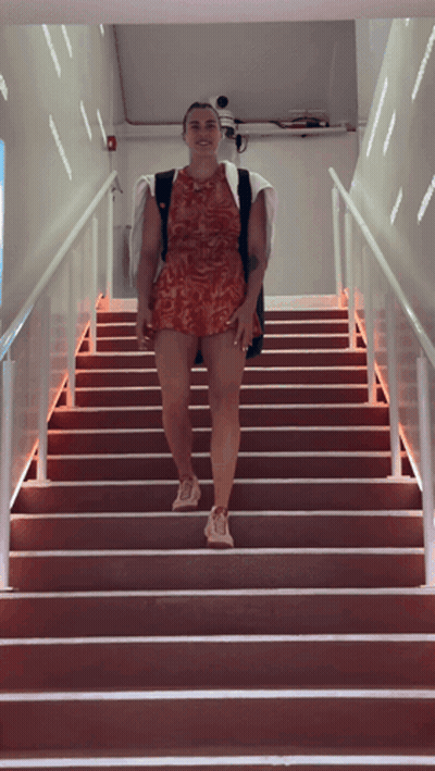 A Woman Is Walking Up A Set Of Stairs GIF