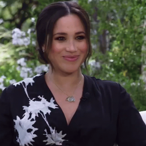 A Woman Is Wearing A Black And White Dress And A Necklace GIF