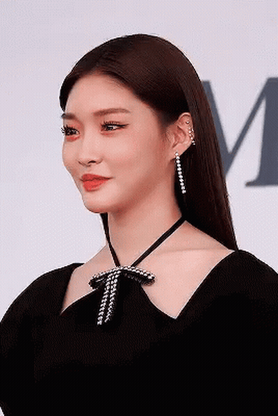 A Woman Is Wearing A Black Dress And Earrings . GIF