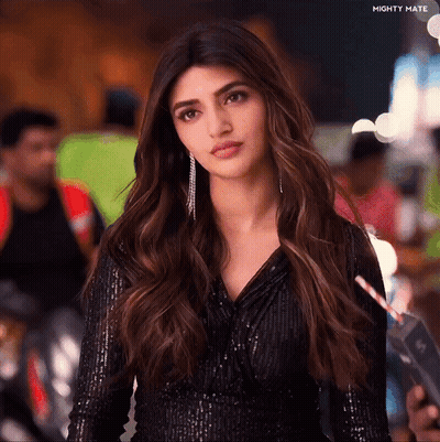 A Woman Is Wearing A Black Sequined Top And Holding A Straw In Her Hand .. GIF