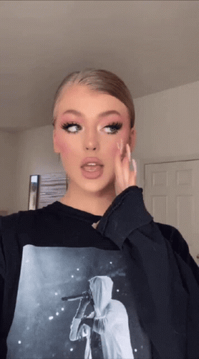 A Woman Is Wearing A Black Sweatshirt With A Picture Of A Person On It GIF