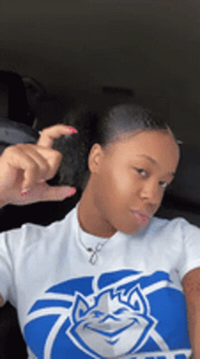 A Woman Is Wearing A Blue And White Shirt With A Duke Logo On It . GIF