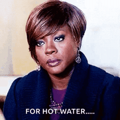 A Woman Is Wearing A Blue Coat And Earrings And Says `` For Hot Water '' . GIF