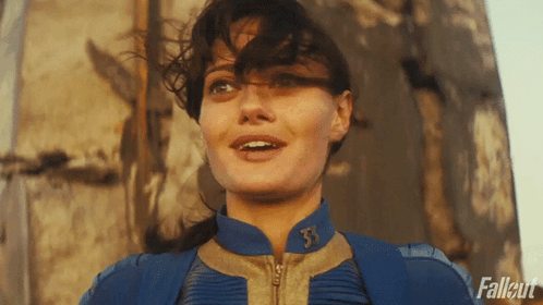 A Woman Is Wearing A Blue Jacket With The Letter T On It GIF