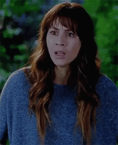 A Woman Is Wearing A Blue Sweater And Making A Funny Face . GIF