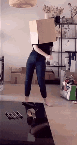 A Woman Is Wearing A Cardboard Box On Her Head . GIF