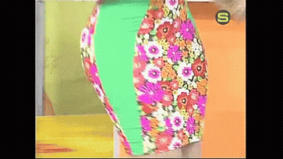 A Woman Is Wearing A Colorful Floral Skirt With A Green Stripe On The Side . GIF