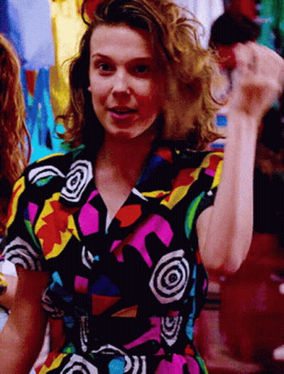A Woman Is Wearing A Colorful Shirt With A Swirl Pattern GIF