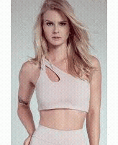 A Woman Is Wearing A Crop Top With A Cut Out On The Side . GIF