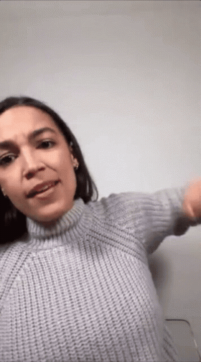 A Woman Is Wearing A Gray Sweater And Making A Funny Face . GIF