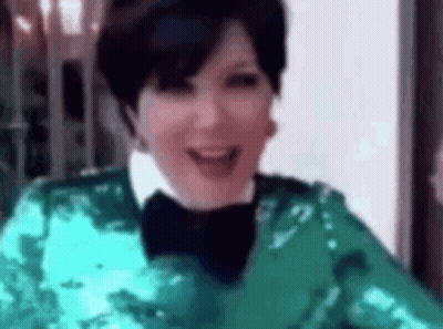 A Woman Is Wearing A Green Sequined Jacket And A Black Bow Tie . GIF