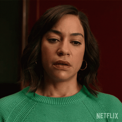 A Woman Is Wearing A Green Sweater With Netflix Written On It GIF