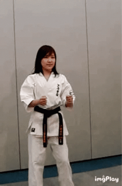 A Woman Is Wearing A Karate Uniform And A Black Belt . GIF