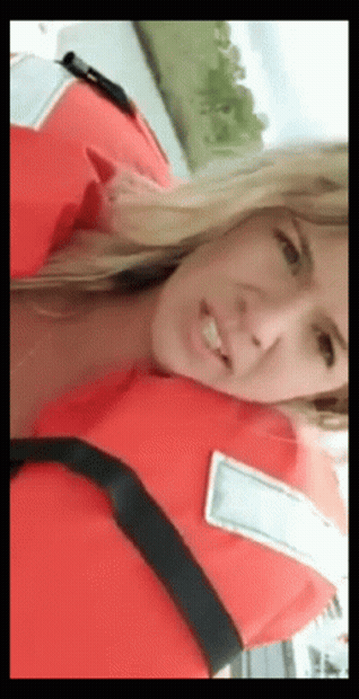 A Woman Is Wearing A Life Jacket And Smiling GIF